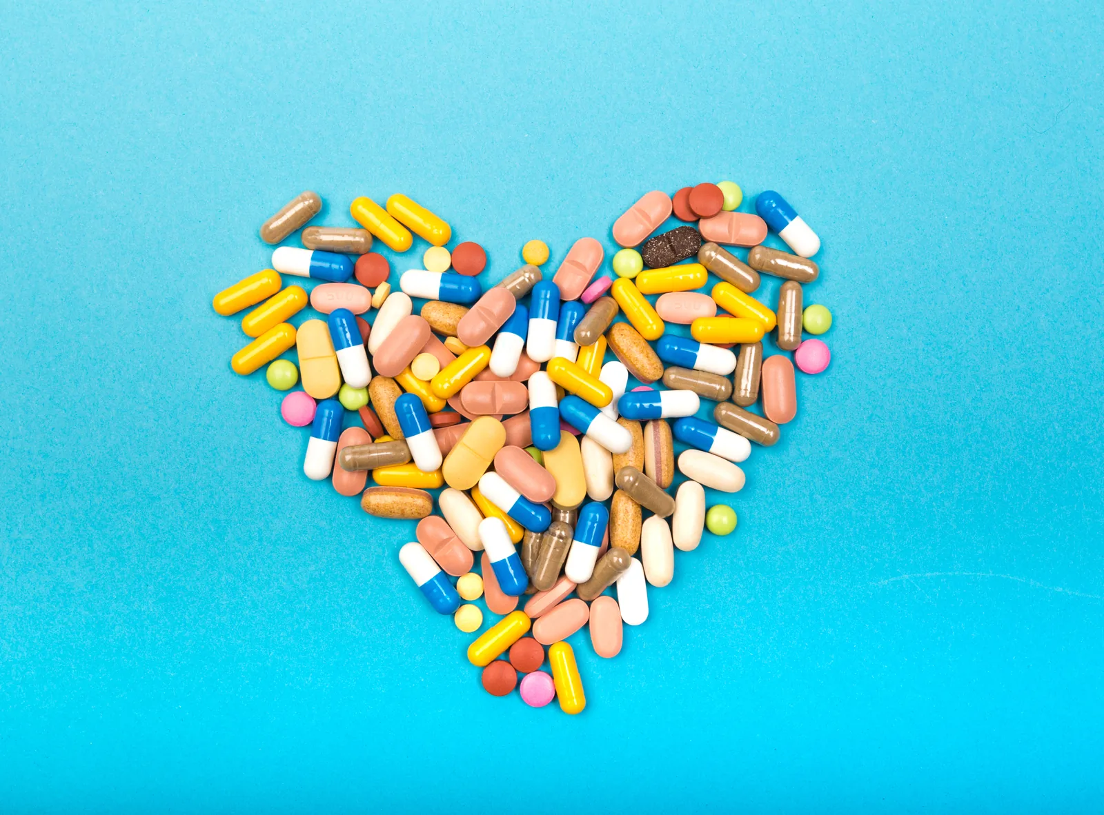 Verschillende erectiepillen en capsules in de vorm van een hart op blauwe achtergrond